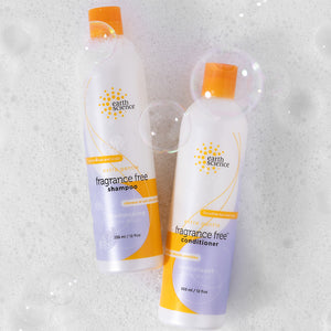Two bottles of Earth Science fragrance-free shampoo and conditioner on a textured white background