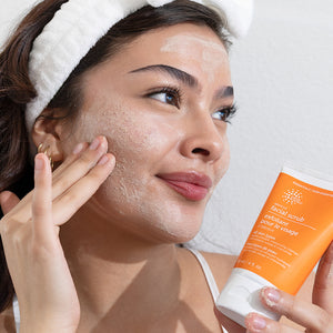 Woman applying facial scrub to her face with a product in hand
