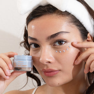 Woman applying eye cream with a focus on skincare