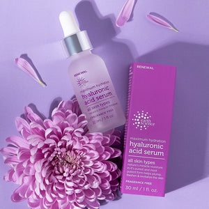 Hyaluronic acid serum bottle and packaging with a pink flower on a purple background