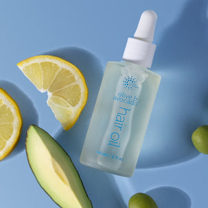 Bottle of olive avocado hair oil with lemon and avocado slices on a blue background