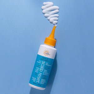 Bottle of olive and avocado scalp rest product with a swirl of white cream on a blue background