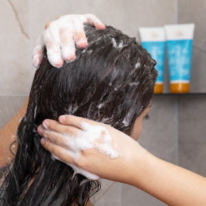 Person washing hair with shampoo in a bathroom setting