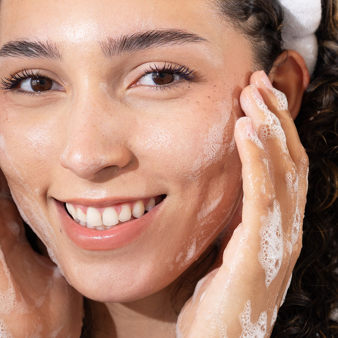 Woman applying a skincare product to her face with a close-up view.